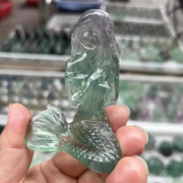 Hand-carved natural fluorite mermaid crystal, featuring translucent green and purple hues for healing and home decor.