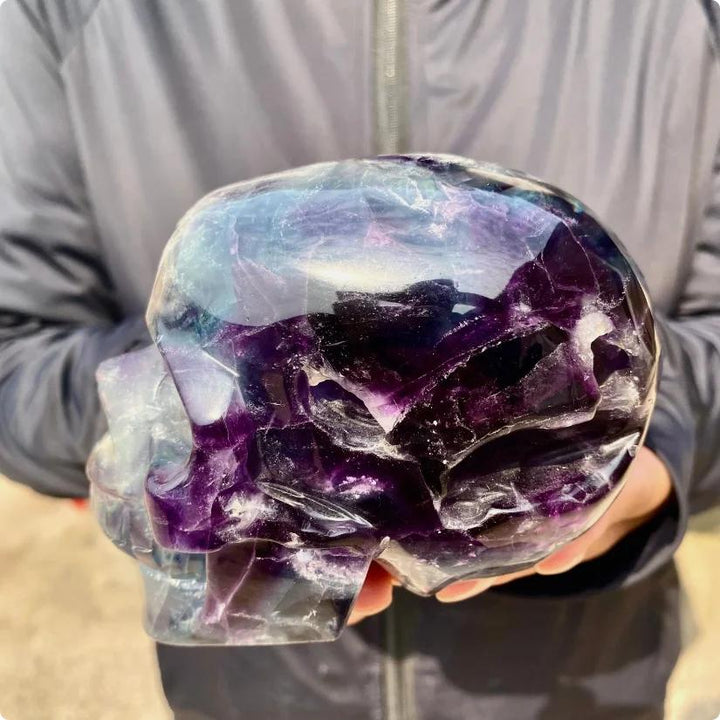 Large Rainbow Fluorite crystal skull, carved with flowing bands of purple, green, blue, and cream.