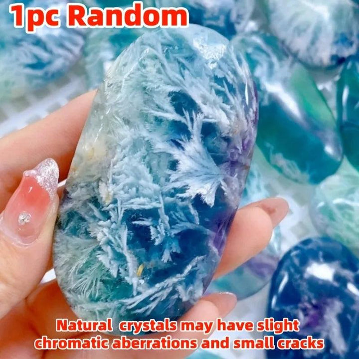 Polished feather snowflake fluorite palm stone featuring vibrant blue and purple hues with unique, natural crystal patterns.