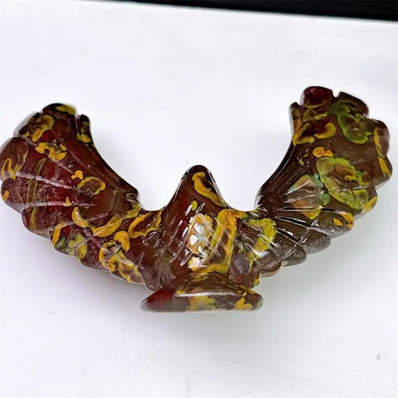 Hand-carved Fruit Jasper eagle spinning statue with vibrant red and yellow patterns for grounding and stability.