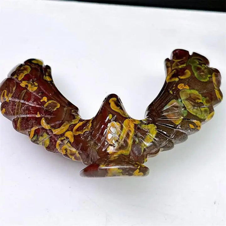 Hand-carved Fruit Jasper eagle spinning statue with vibrant red and yellow patterns for grounding and stability.
