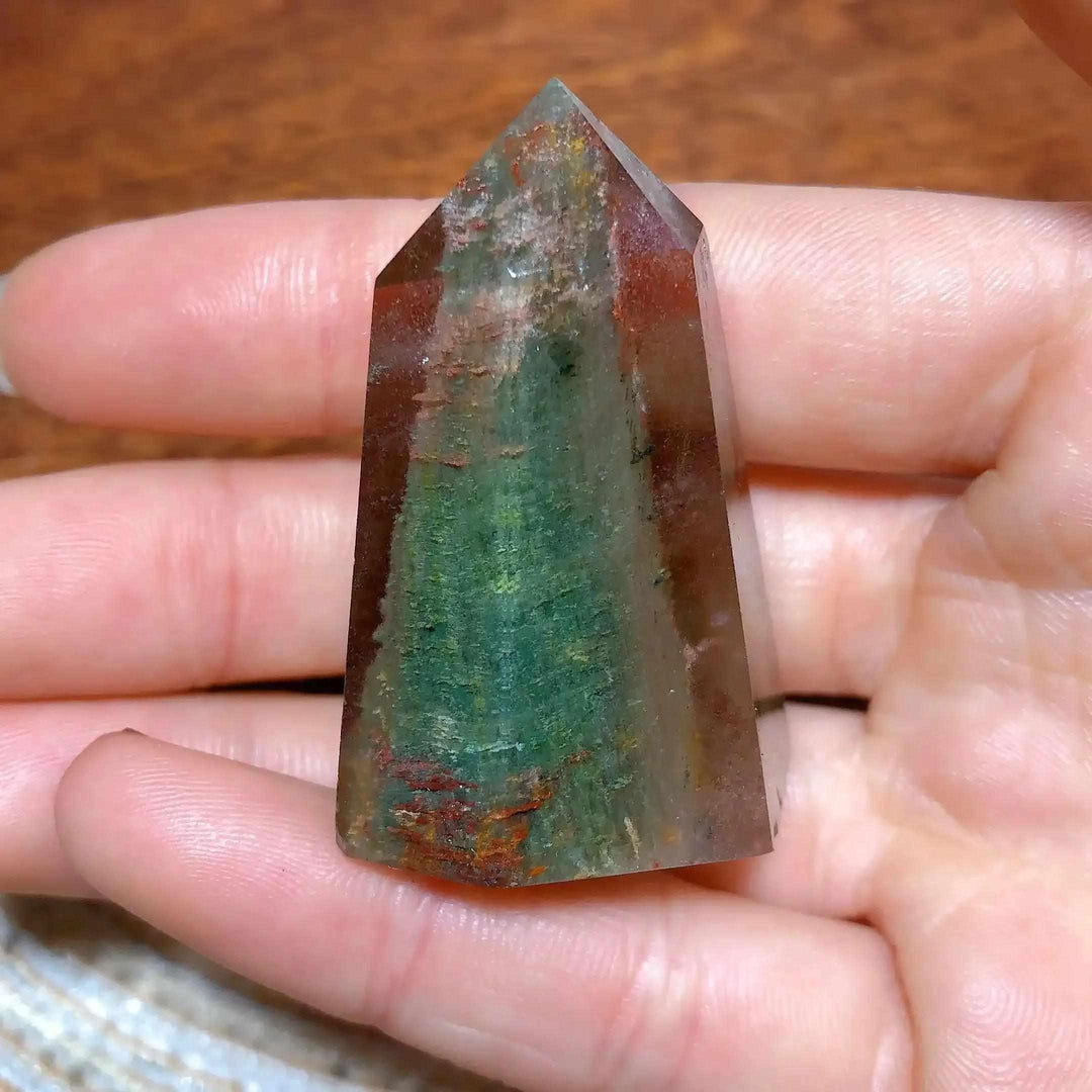 Polished Garden Quartz tower point featuring mossy green and earthy red inclusions for grounding and clarity.