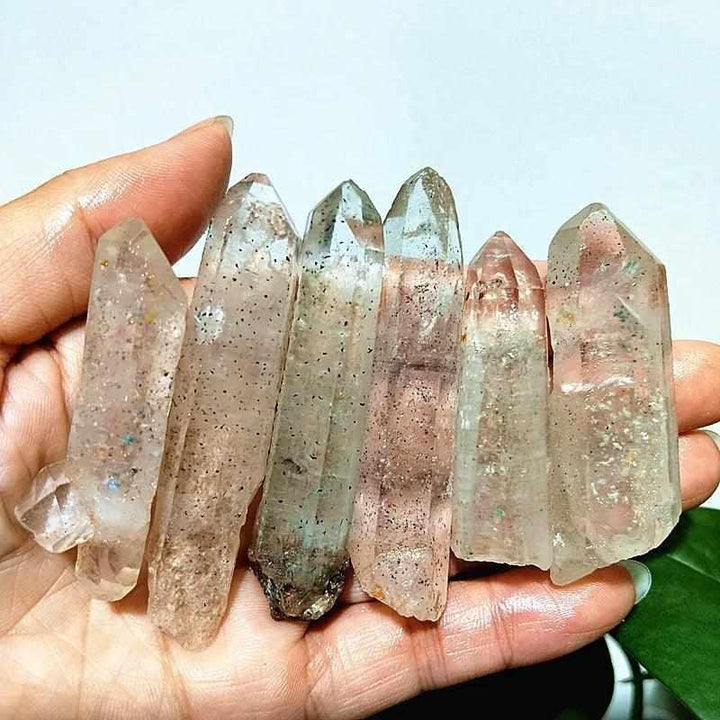 Handheld Garden and Strawberry Quartz points featuring mossy green inclusions and red flecks for heart chakra healing.