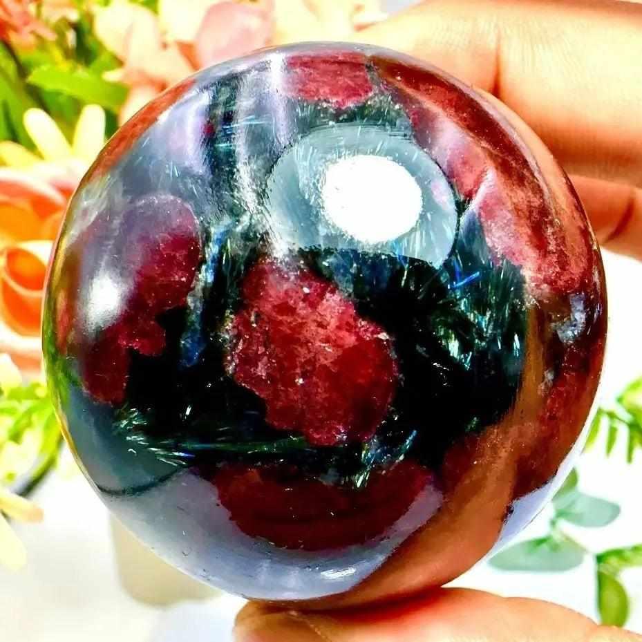 Polished Garnet Astrophyllite sphere featuring golden blades and deep red garnet for grounding and inner growth.