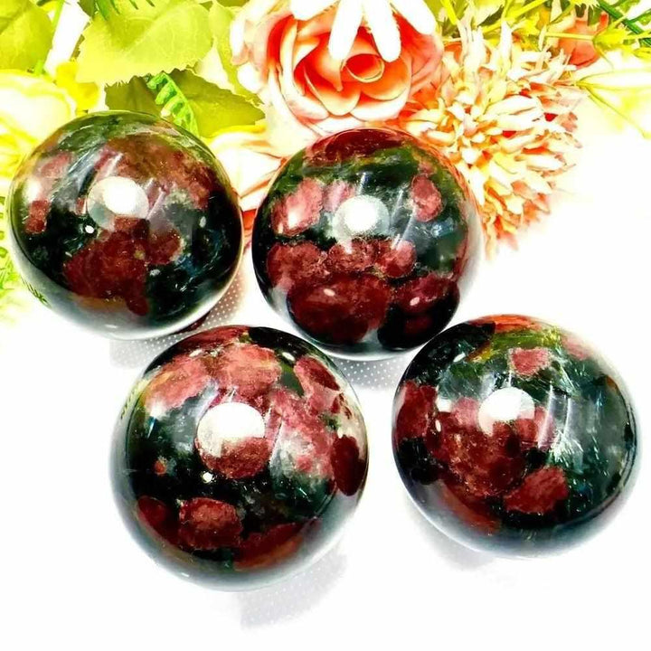 Polished Garnet Astrophyllite spheres featuring golden star-like blades and deep red garnet for grounding and vitality.