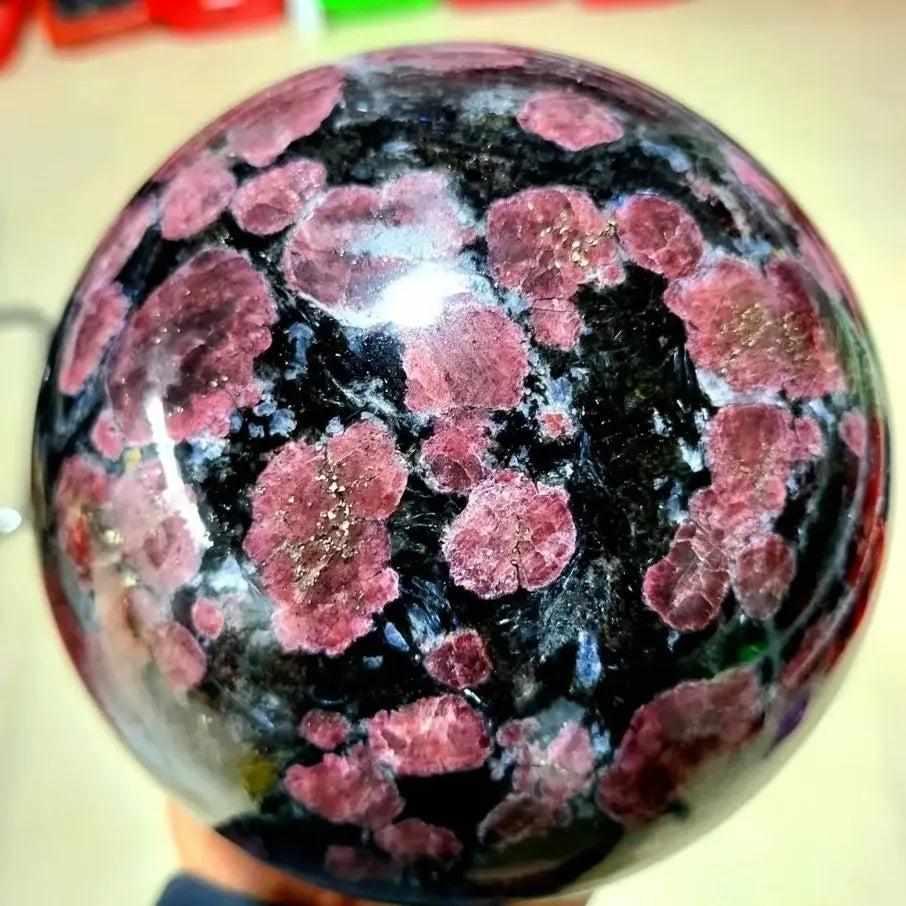 Polished Garnet Astrophyllite sphere featuring golden blades and deep red garnet for root chakra grounding and vitality.