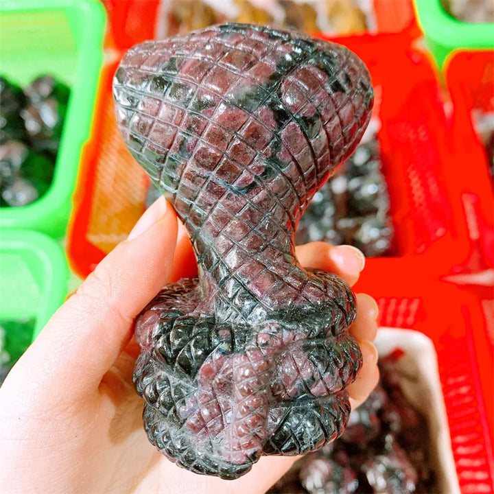 Deep red garnet crystal carved into a striking cobra snake, symbolizing grounded courage and sacred power.