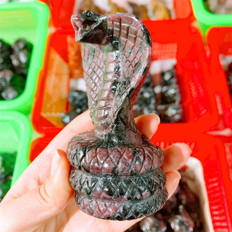 Deep red garnet crystal carved into a striking cobra snake, symbolizing grounded courage and sacred transformation.