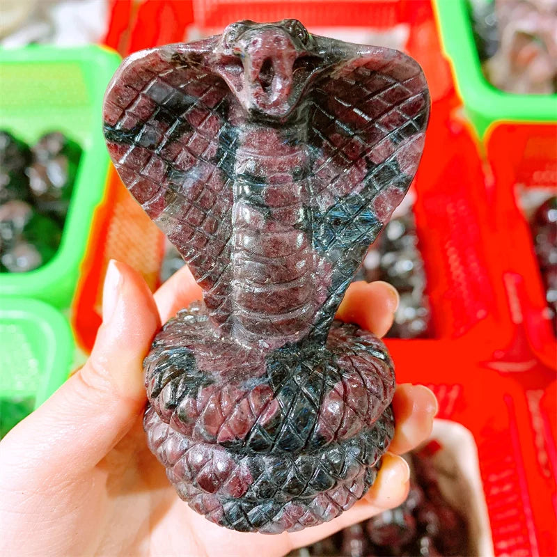 Deep red garnet crystal carved into a striking cobra snake, symbolizing sacred power, vitality, and grounded confidence.