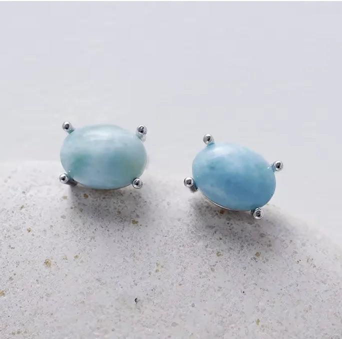 Oval Larimar gemstone stud earrings in silver settings, offering calming energy and a serene blue aesthetic.