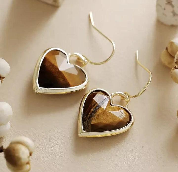 Heart-shaped Tiger's Eye gemstone drop earrings in a gold setting, perfect for grounding energy and daily style.