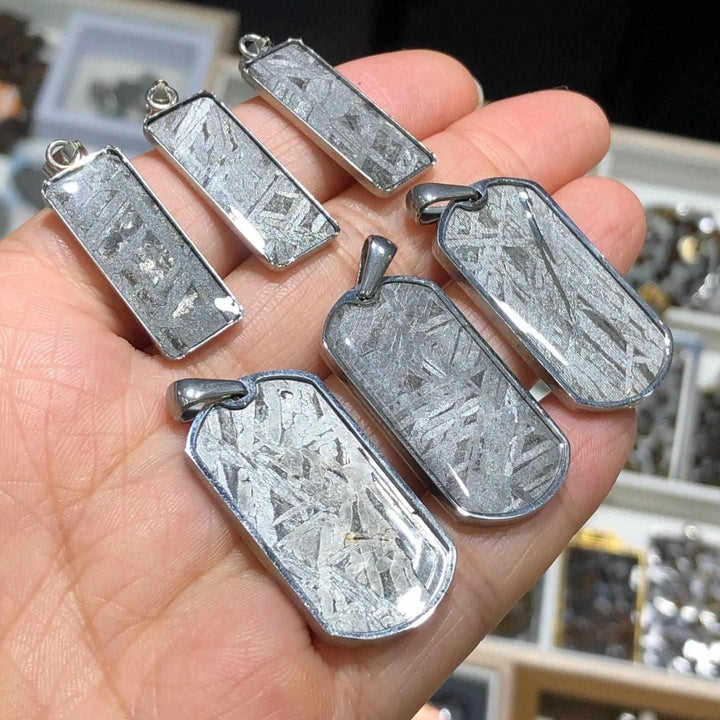 Gibeon meteorite pendants in stainless steel frames, showcasing unique silver Widmanstatten patterns for cosmic grounding.