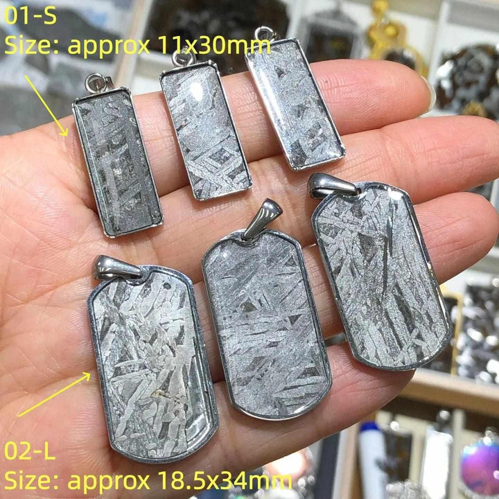 Gibeon meteorite pendants in stainless steel frames, featuring unique silver Widmanstatten patterns for cosmic grounding.