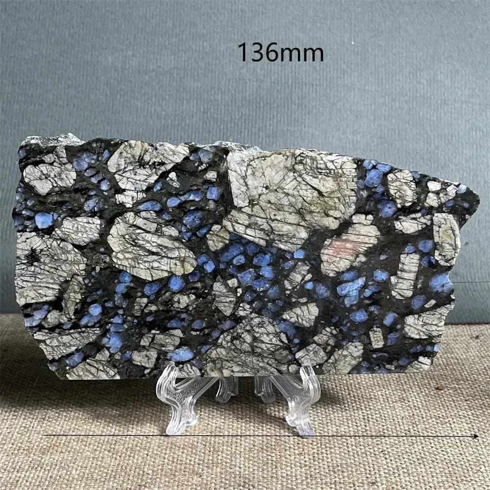 Polished Glaucophane slab from Crystal Destiny, featuring deep blue-gray crystals in a black and white matrix on a stand.