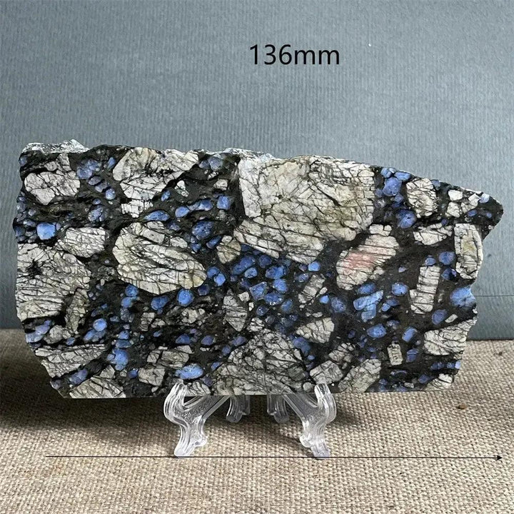 Polished Glaucophane slab from Crystal Destiny, featuring deep blue-gray crystals in a black and white matrix on a stand.