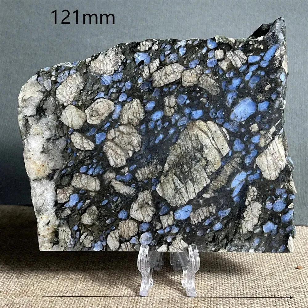 Polished Glaucophane slab from Crystal Destiny, featuring deep blue-gray and white mineral inclusions on a stand.