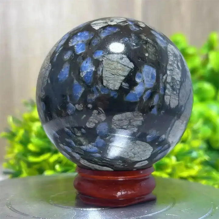 Polished Glaucophane Que Sera crystal sphere with striking blue and grey patterns for Reiki healing and home decor.