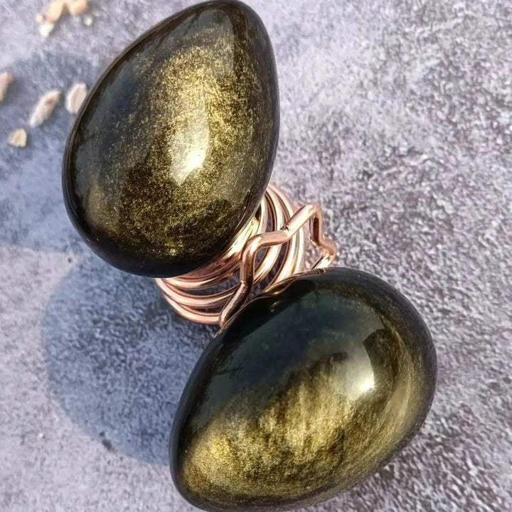 Two polished Gold Obsidian Crystal Eggs, dark volcanic glass with golden shimmer, for manifestation and grounding.
