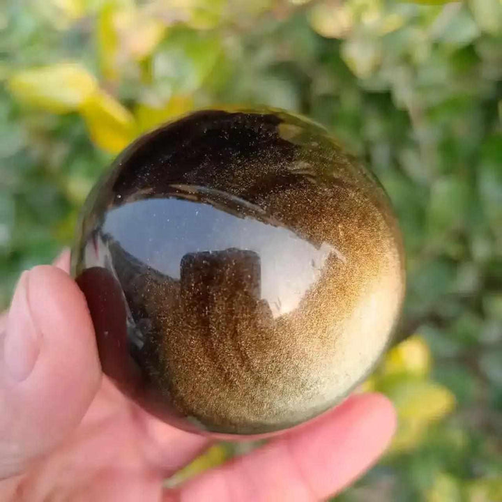 Polished Gold Sheen Obsidian sphere with a warm, glowing golden shimmer, perfect for grounding and personal power.