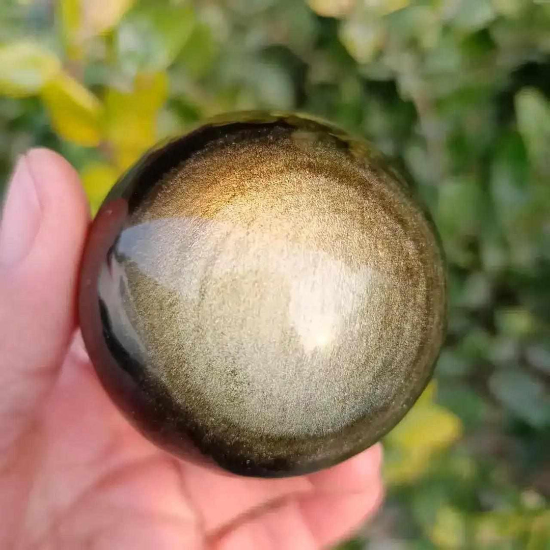 Hand-polished Gold Sheen Obsidian sphere featuring a radiant golden glow in black volcanic glass for grounding energy.