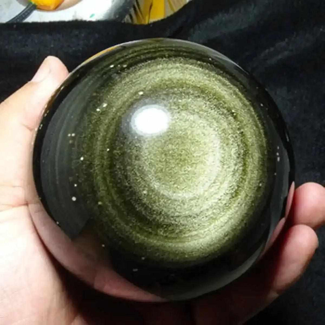 Hand-polished Gold Sheen Obsidian sphere featuring a mesmerizing golden glow and protective volcanic glass energy.