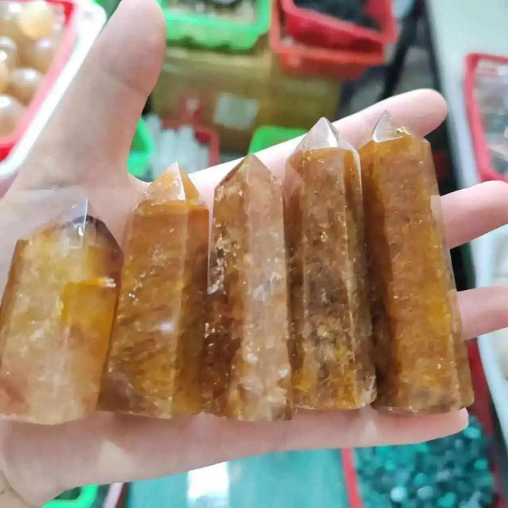 Handheld Golden Healer Quartz obelisk featuring warm yellow tones, polished hexagonal points, and natural iron inclusions.