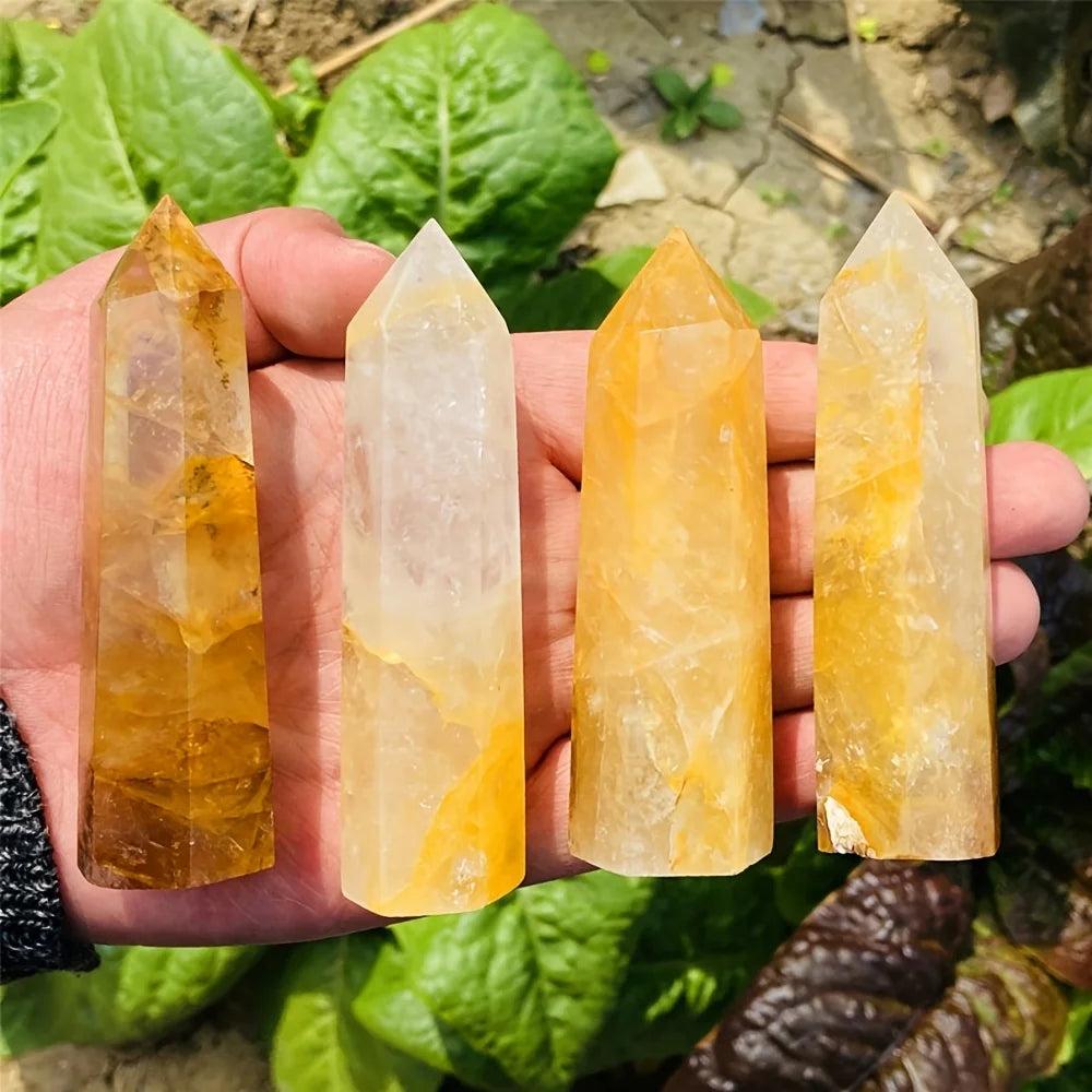 Four Golden Quartz Crystal Towers in hand, showing warm amber hues for confidence and healing.