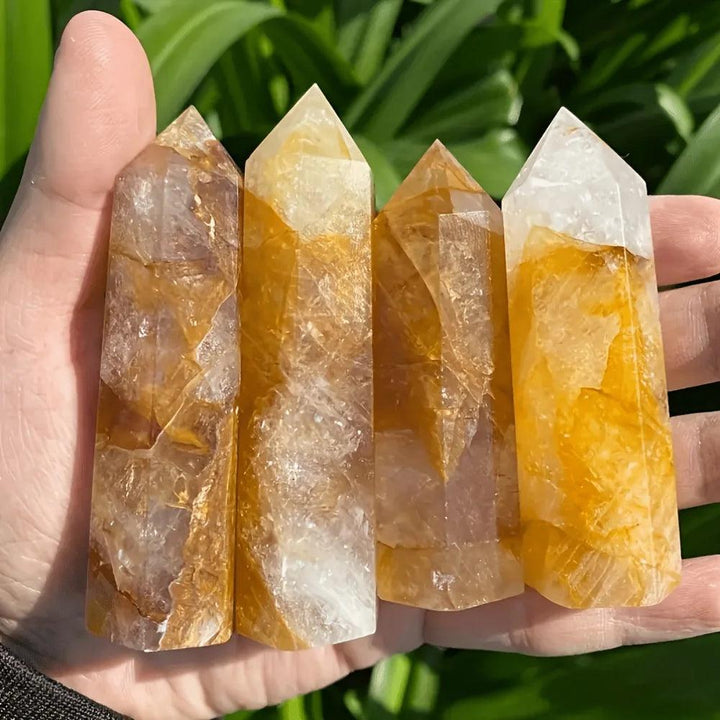 Four Golden Quartz Crystal Towers with warm amber hues held in a hand for solar plexus healing.