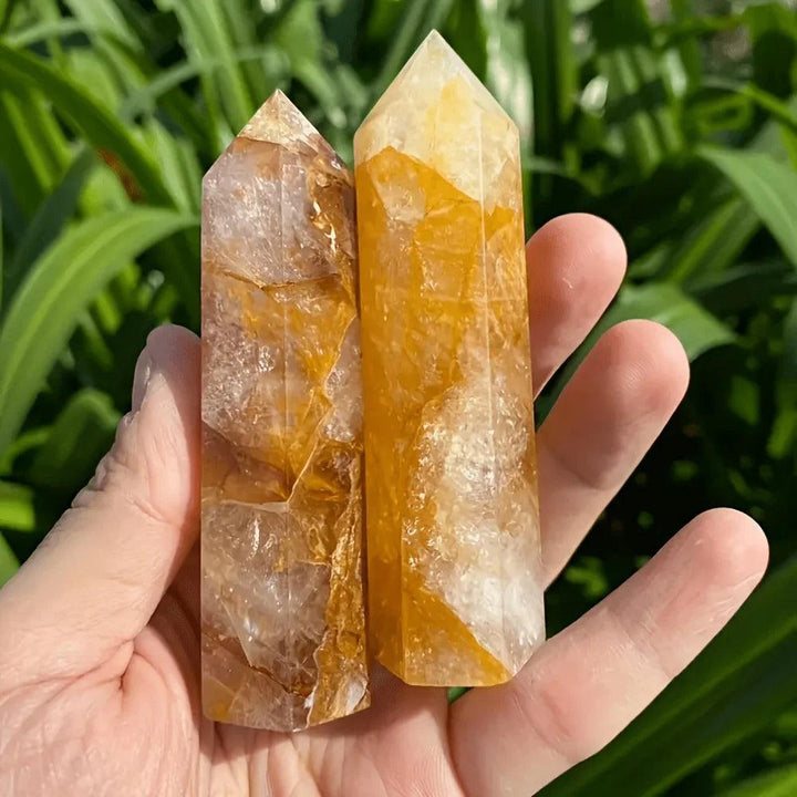 Two Golden Quartz Crystal Towers with warm amber inclusions held in a hand for healing and manifestation.