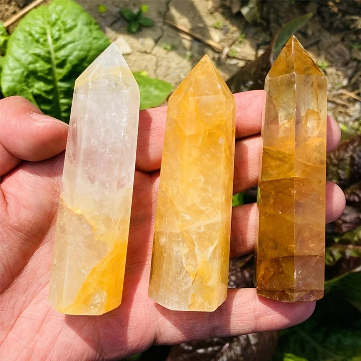 Three Golden Quartz Crystal Towers in pale champagne to deep amber gold, held in hand for solar plexus healing.