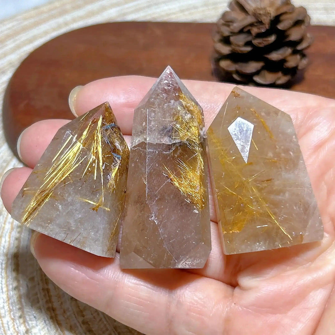 Hand-held Golden Rutilated Quartz towers featuring clear crystal with shimmering golden rutile needles and faceted points.