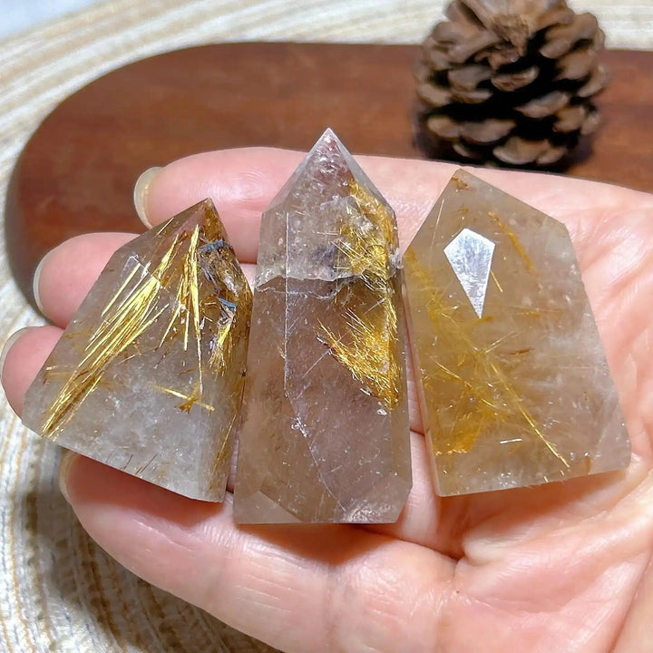 Hand-held Golden Rutilated Quartz towers featuring clear crystal with shimmering golden rutile needles and faceted points.