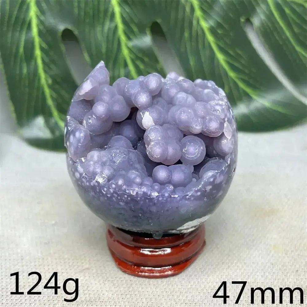 Indonesian Grape Agate crystal sphere with botryoidal formations, lilac to deep purple, on a wooden stand.
