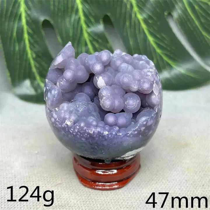 Indonesian Grape Agate crystal sphere with botryoidal formations, lilac to deep purple, on a wooden stand.