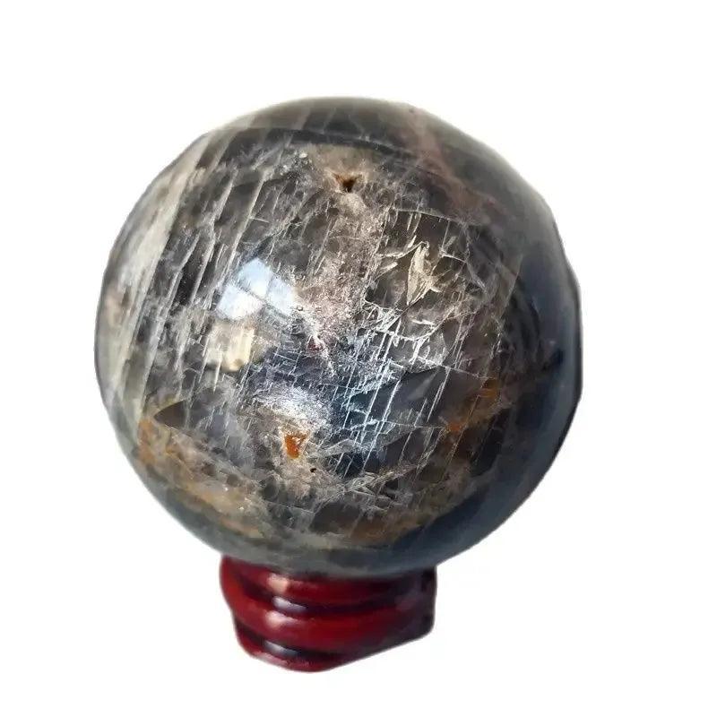 Gray Moonstone crystal sphere from Crystal Destiny, showcasing silvery-gray shimmer and blue-white adularescence on a red stand.
