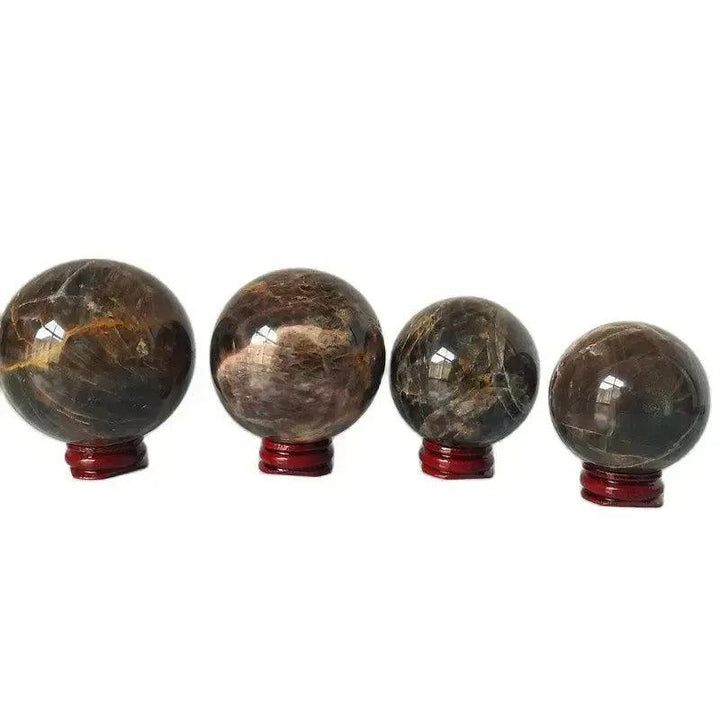 Four polished Gray Moonstone crystal spheres of varying sizes on red stands from Crystal Destiny.