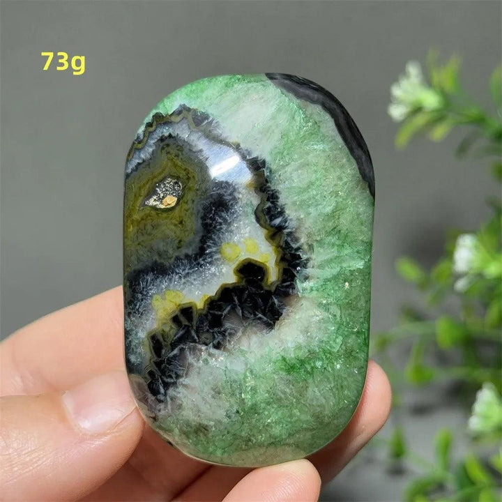 Polished 73g natural green agate palm stone with unique black and yellow crystal patterns for healing and meditation.