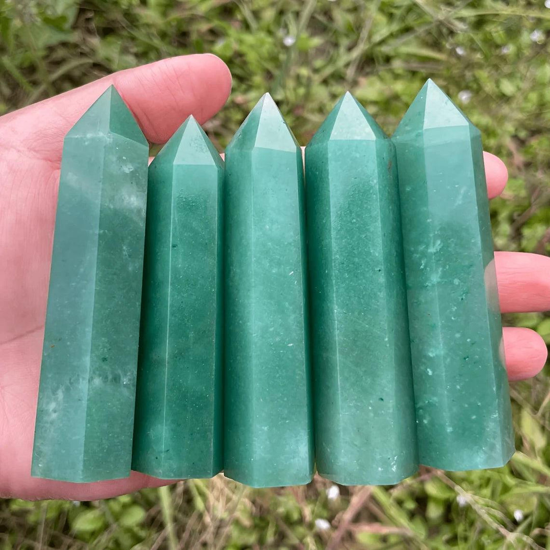 Five polished Green Aventurine Crystal Towers held in hand, showing natural green shimmer for heart chakra healing.
