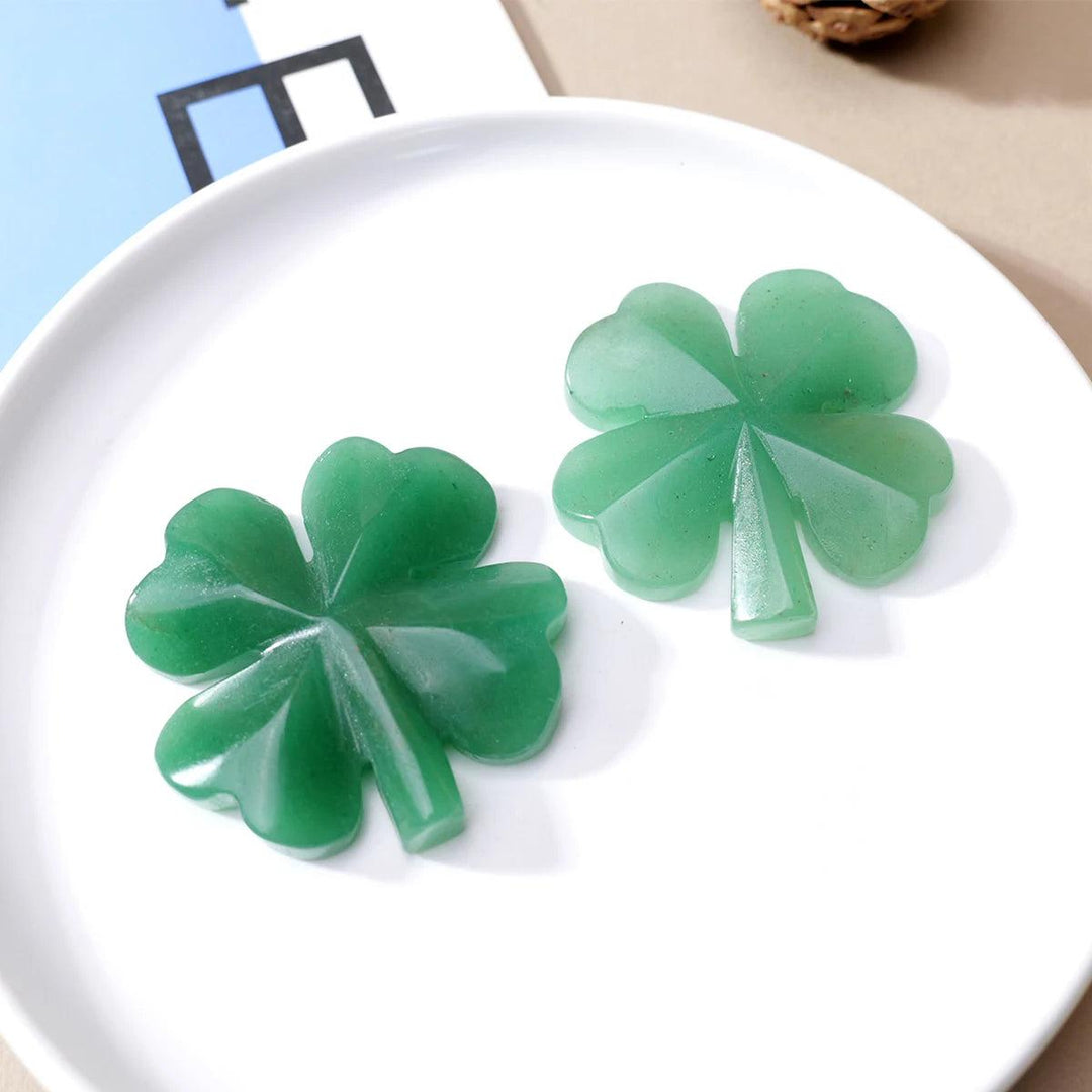 Two smooth, hand-polished green aventurine four-leaf clover carvings on a white plate, symbolizing luck and growth.