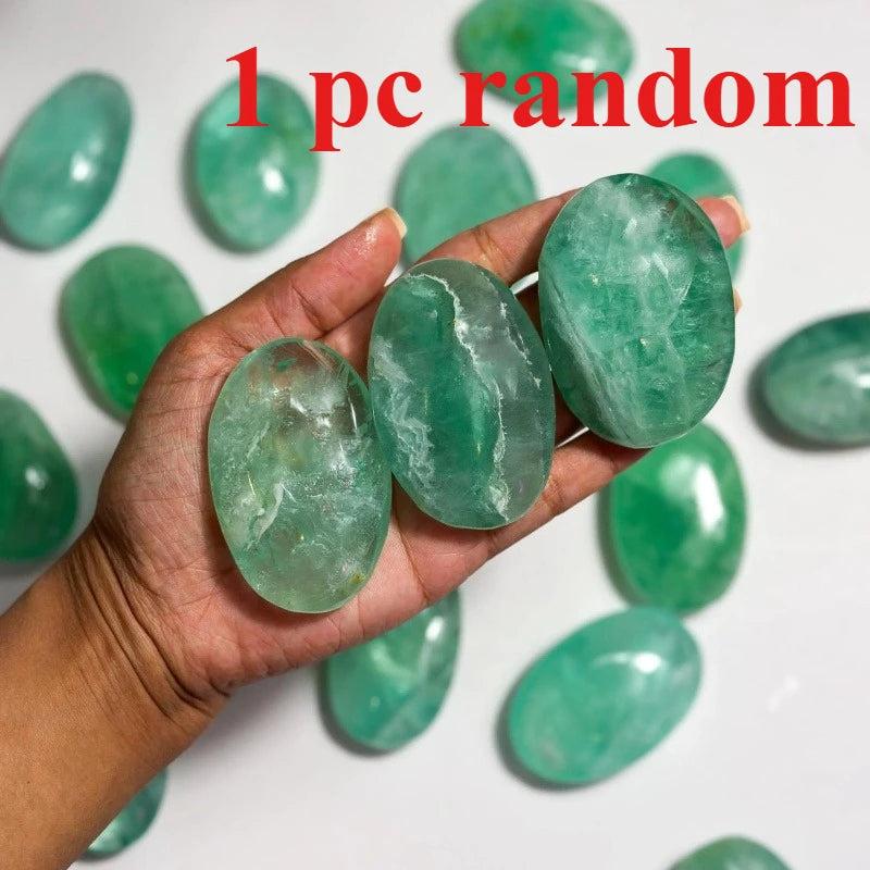 Polished green fluorite palm stones held in hand, showcasing natural healing crystal textures.