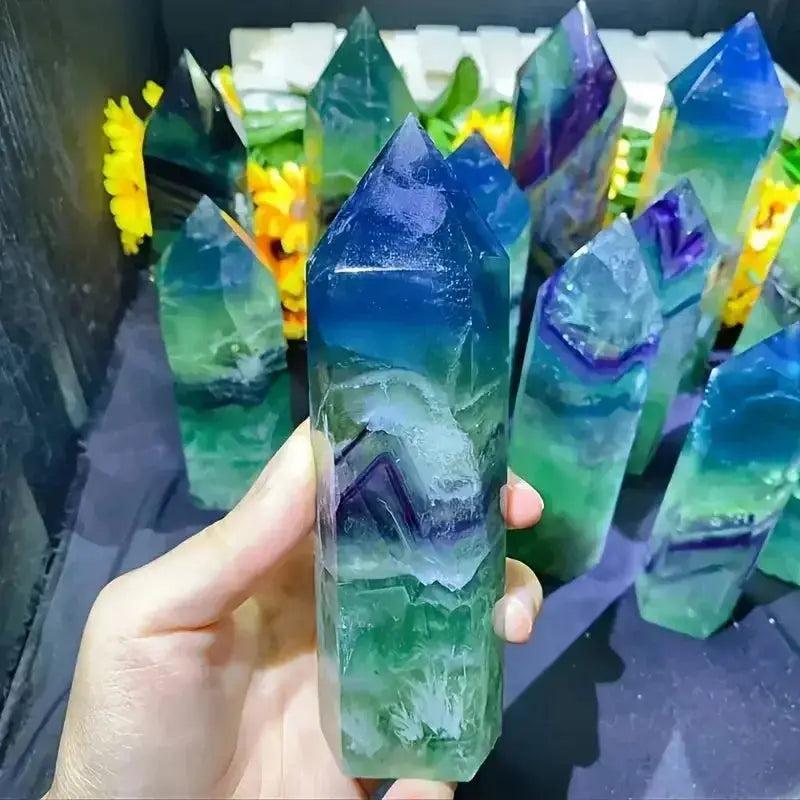 Hand holding a vibrant Green Fluorite Crystal Tower Obelisk, showcasing its layered green and purple hues for mental clarity.