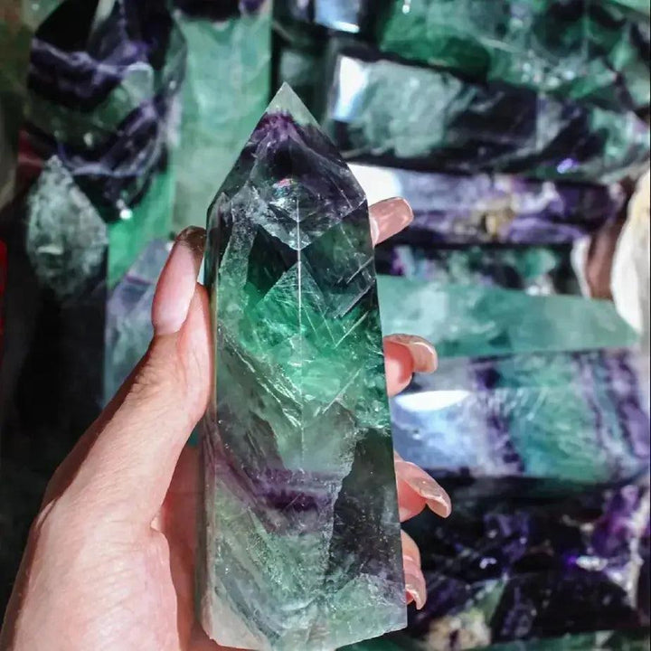 Hand holding a polished Green Fluorite Crystal Tower Obelisk, showcasing its vibrant green and purple bands for mental clarity.