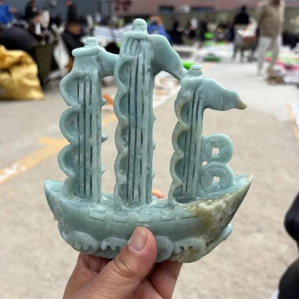 Hand-carved green jade sailboat statue, a symbol of abundance and prosperity for Heart Chakra healing and manifestation.