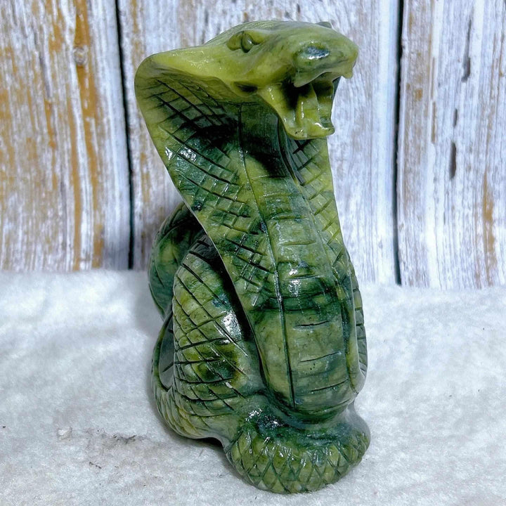 Green jasper cobra carving with intricate scales, a grounding stone sculpture for heart chakra healing and protection.