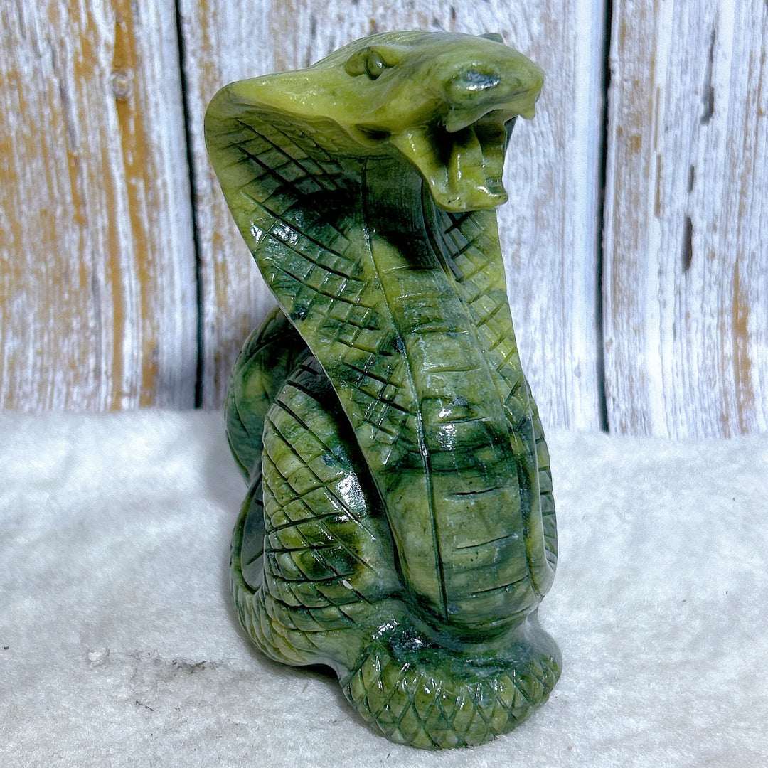 Green jasper cobra carving with intricate scales, a grounding stone sculpture for heart chakra healing and protection.