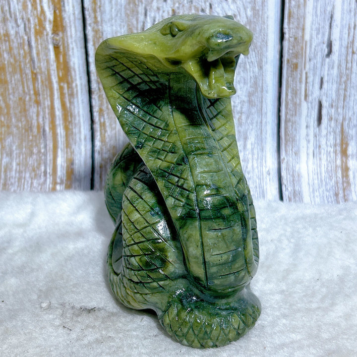 Green jasper cobra carving with intricate scales, a grounding stone sculpture for heart chakra healing and protection.