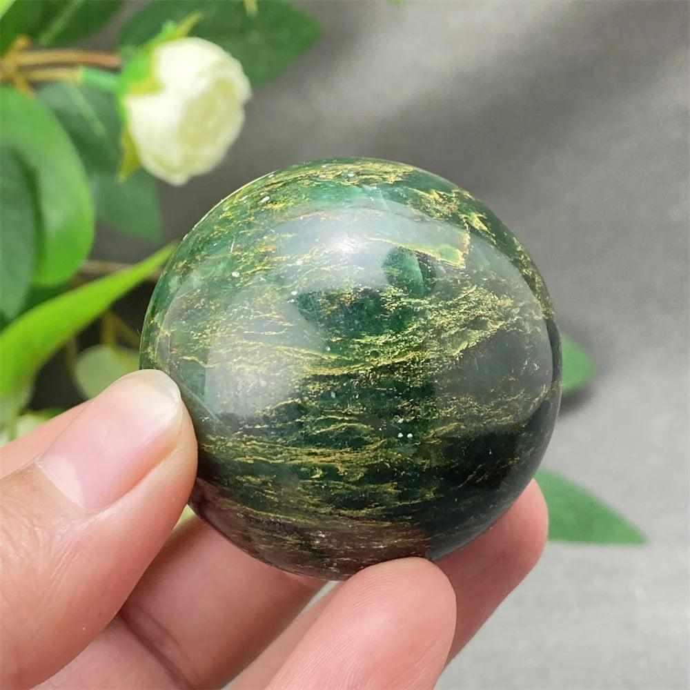 Polished Green Verdite sphere with rich, deep green tones for grounding, held in hand to showcase its glossy finish.