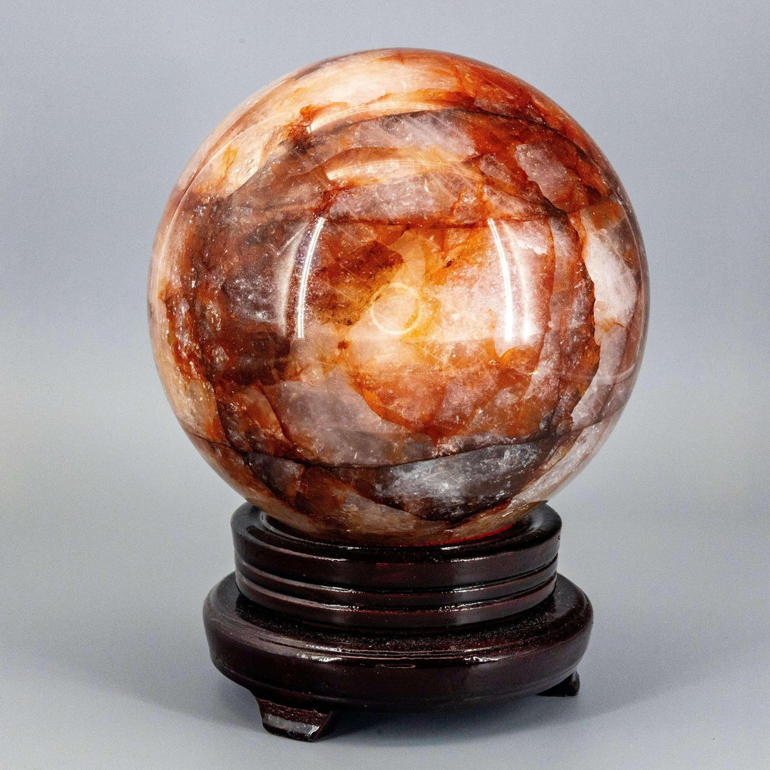 Commanding 158mm Hematoid "Fire" Quartz Sphere radiating grounding and amplifying energy on a dark wood stand.