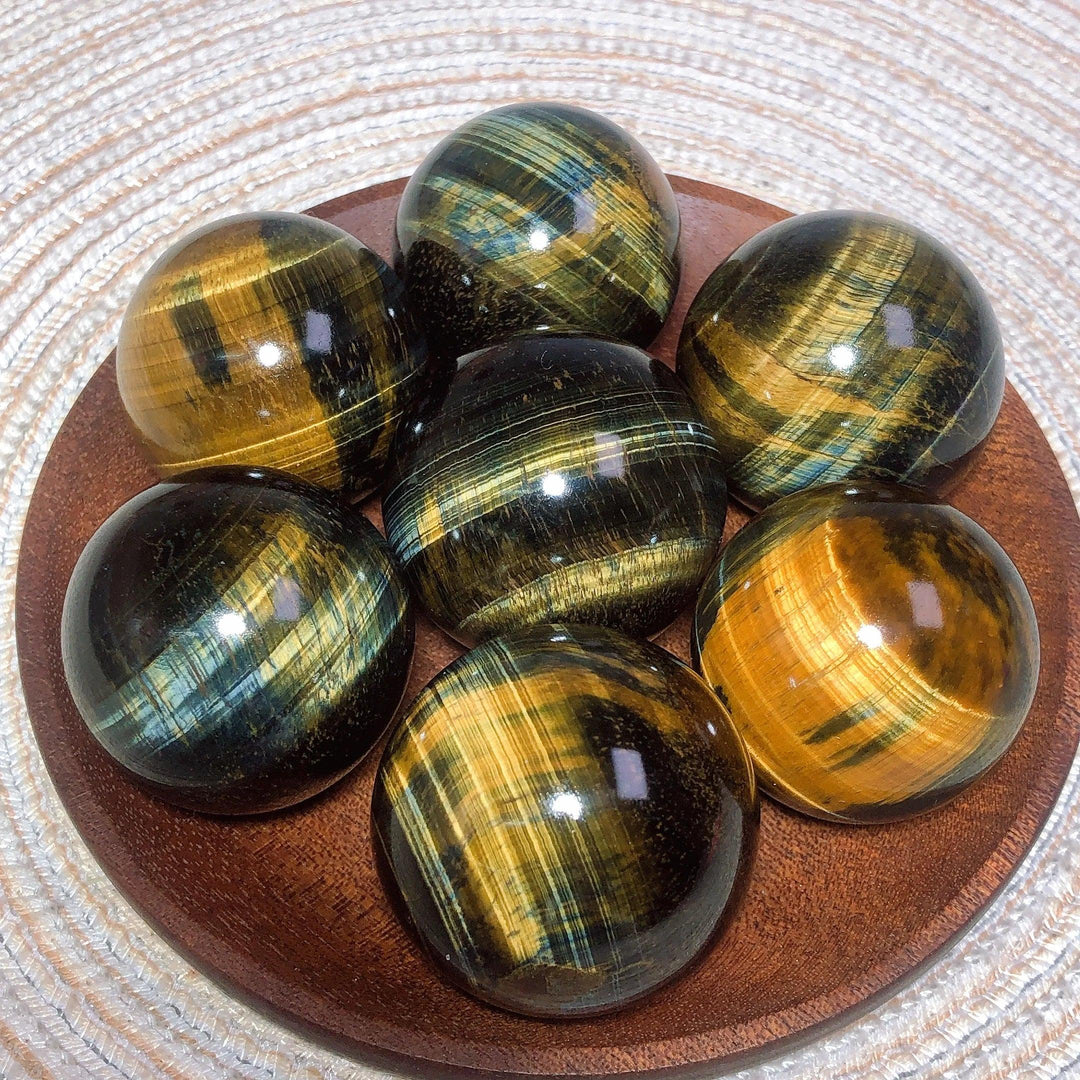 Polished blue and yellow Tiger Eye crystal spheres with flashy chatoyancy, perfect for healing energy and home decor.