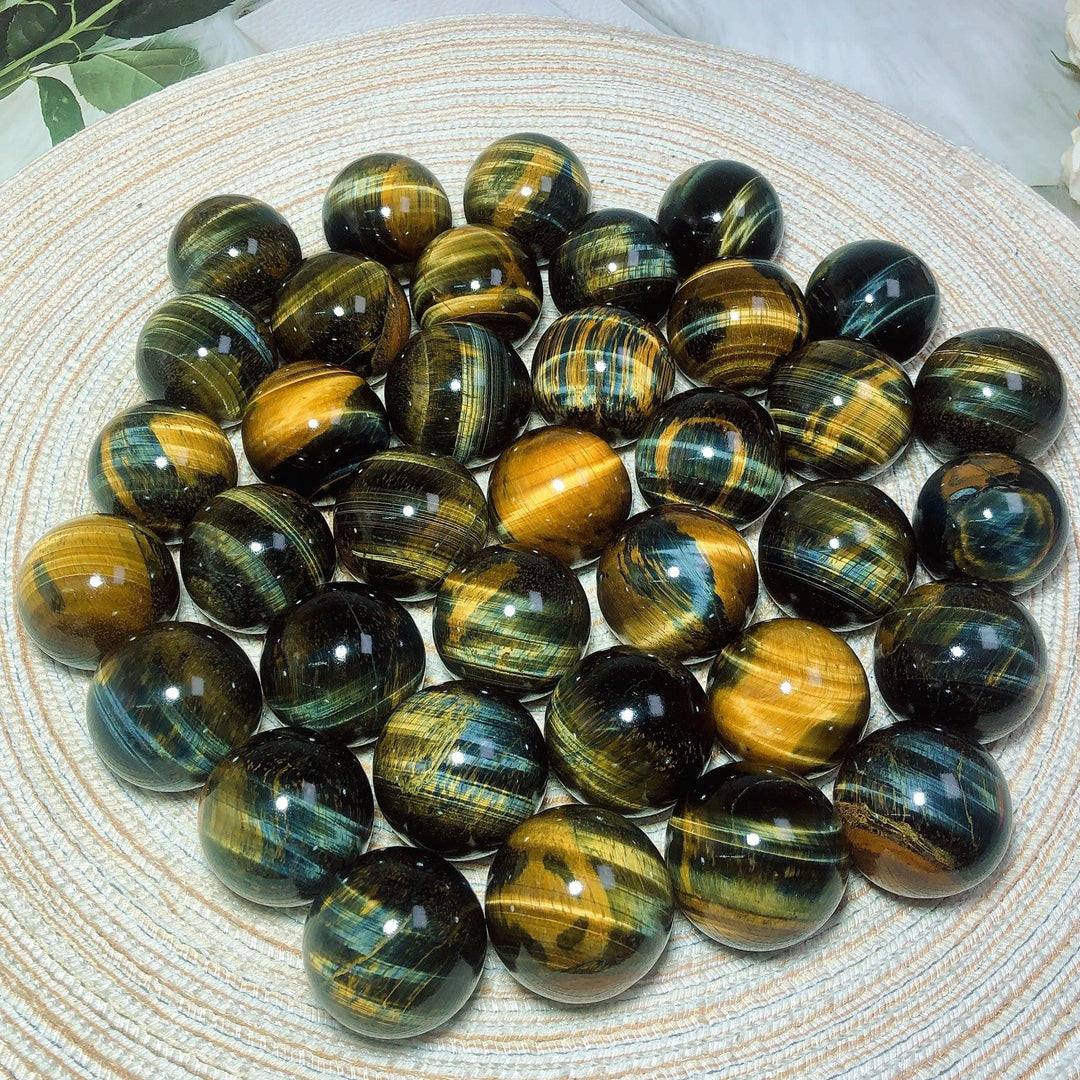 Polished blue and yellow Tiger Eye crystal spheres featuring flashy, natural mineral patterns for healing and home decor.